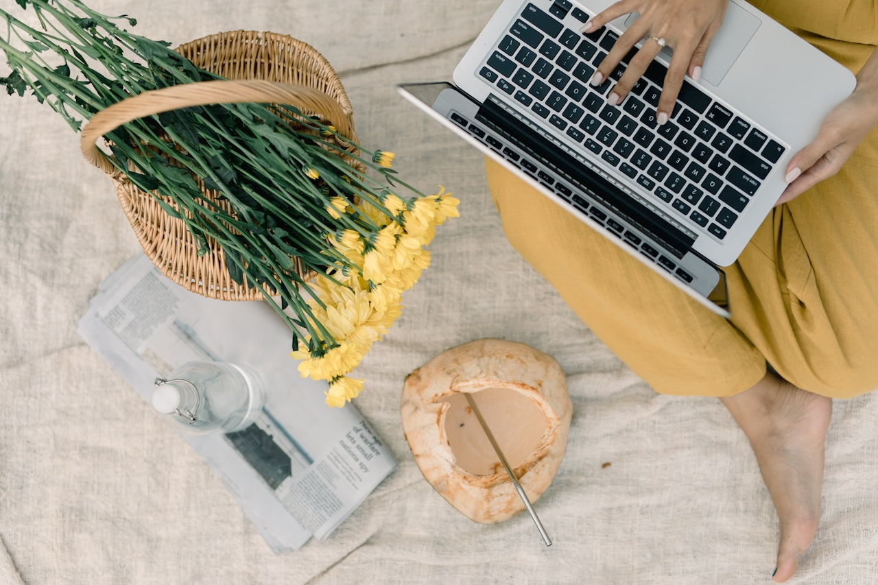 Blote voeten, bloemen en laptop. Het is lente en persoon heeft gezonde huid door de multi use balm